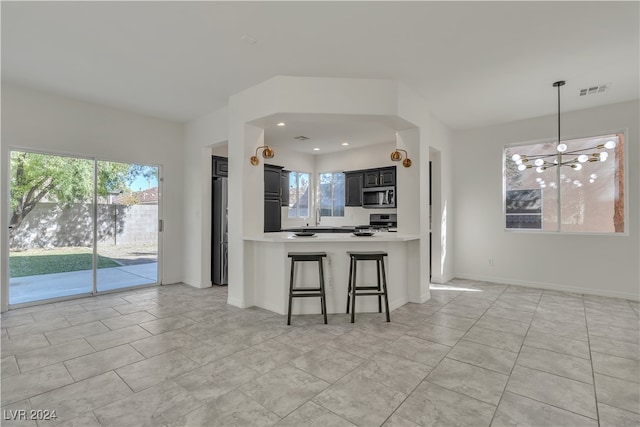 kitchen featuring sink, a breakfast bar area, an inviting chandelier, kitchen peninsula, and stainless steel appliances