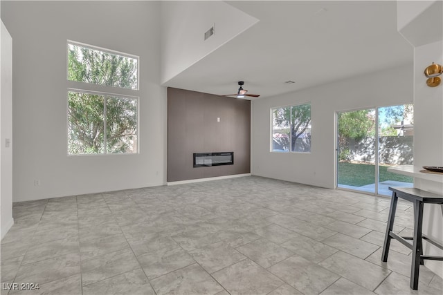 unfurnished living room with ceiling fan, a large fireplace, and heating unit