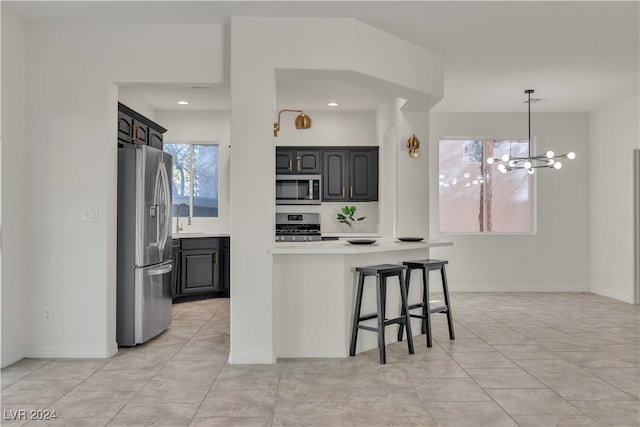 kitchen with a breakfast bar, sink, an inviting chandelier, pendant lighting, and stainless steel appliances