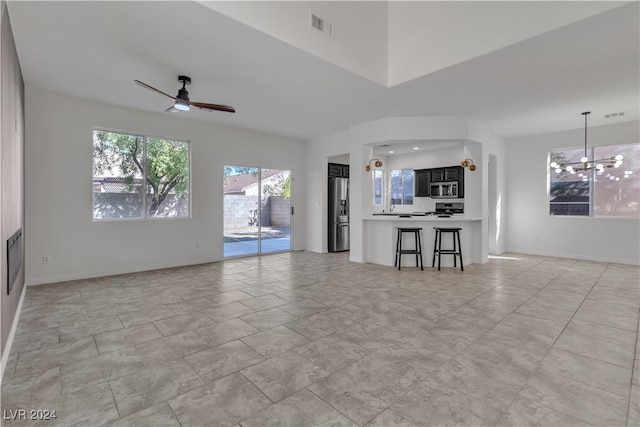 unfurnished living room with ceiling fan with notable chandelier