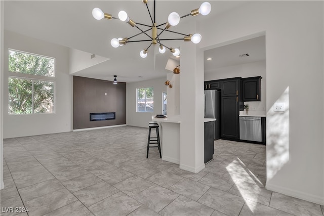 kitchen featuring appliances with stainless steel finishes, ceiling fan with notable chandelier, and a kitchen breakfast bar