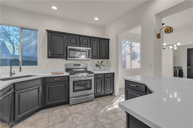 kitchen with washing machine and dryer, appliances with stainless steel finishes, sink, and plenty of natural light