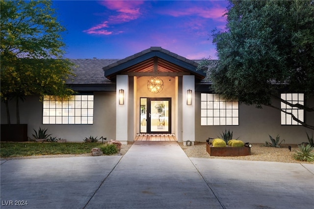 exterior entry at dusk featuring stucco siding