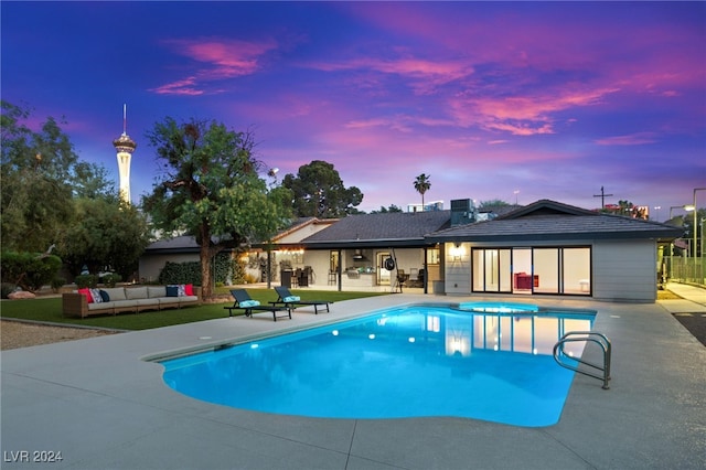 pool at dusk featuring a patio and outdoor lounge area