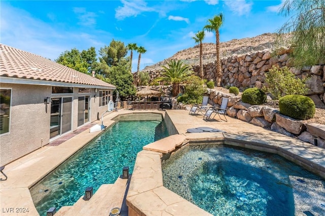 view of pool with an in ground hot tub, a mountain view, and a patio