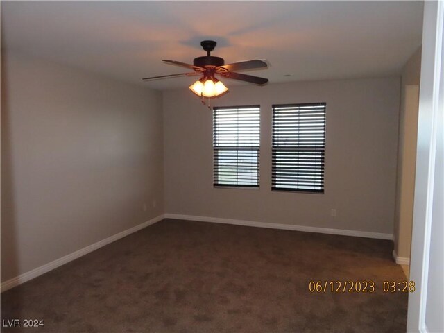 spare room with ceiling fan and dark carpet