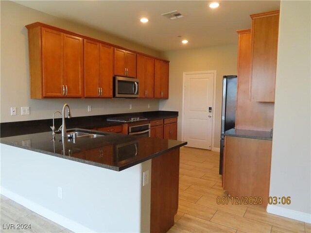 kitchen featuring dark stone countertops, appliances with stainless steel finishes, sink, and kitchen peninsula