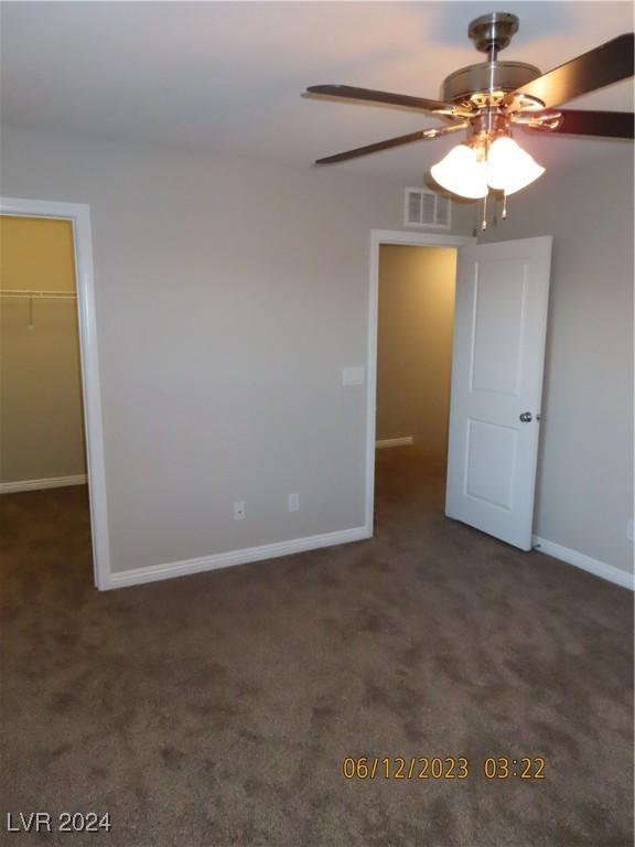 empty room with ceiling fan and dark carpet