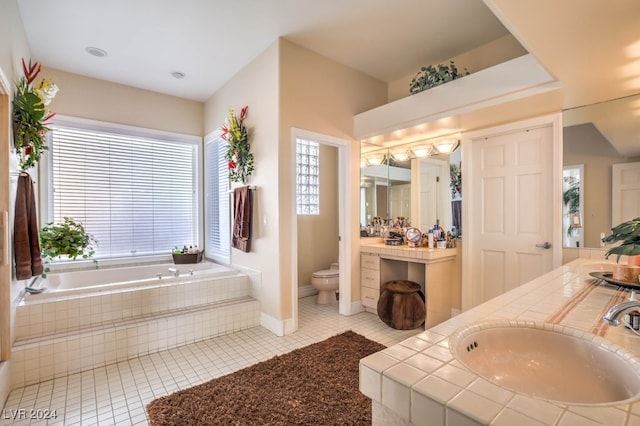 bathroom featuring vanity, tile patterned floors, tiled bath, and toilet