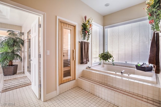 bathroom with tiled tub and tile patterned floors