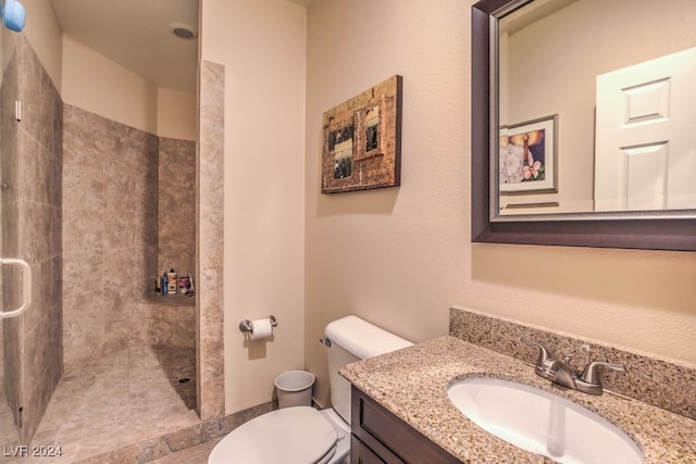 bathroom with vanity, toilet, and a tile shower