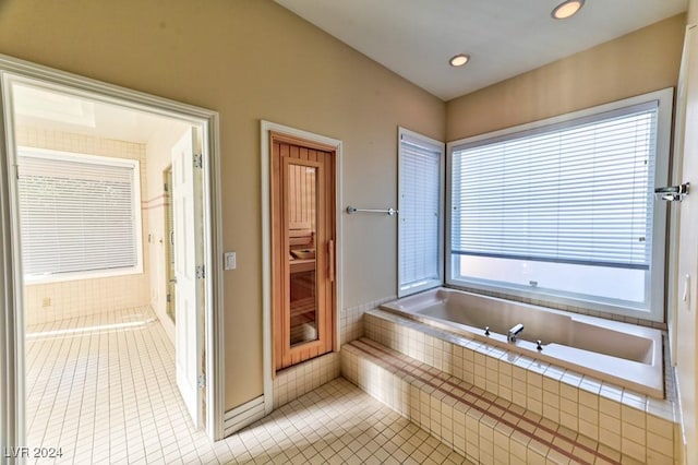 bathroom with a relaxing tiled tub and tile patterned floors