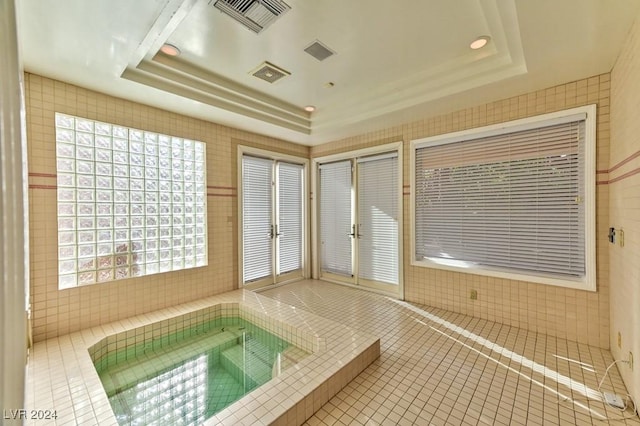 bathroom with tile patterned floors, a raised ceiling, and tile walls