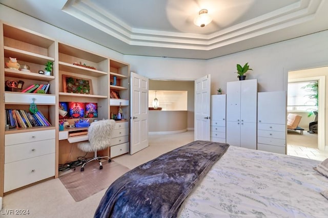 bedroom featuring light carpet and a tray ceiling