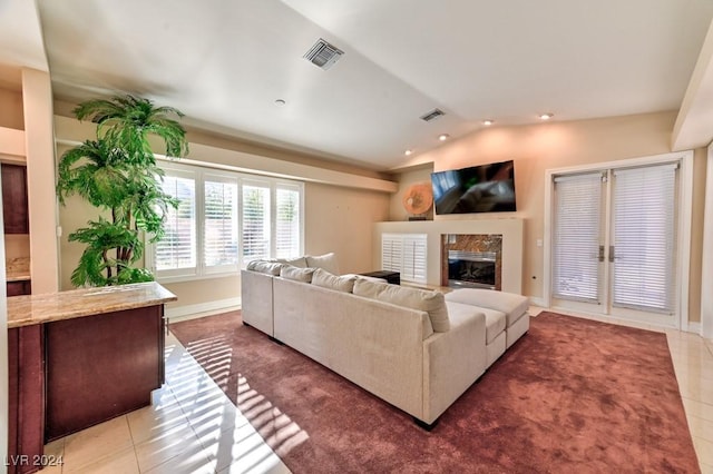 tiled living room with a high end fireplace and vaulted ceiling