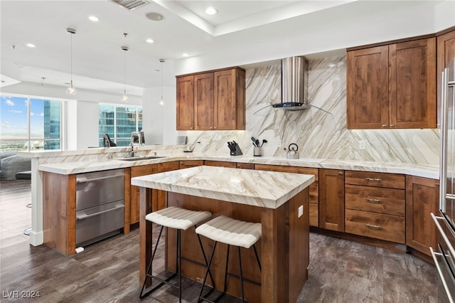 kitchen featuring a breakfast bar, a center island, pendant lighting, backsplash, and a sink