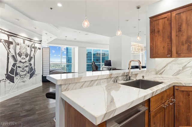 kitchen with light stone countertops, dishwasher, brown cabinets, and a sink