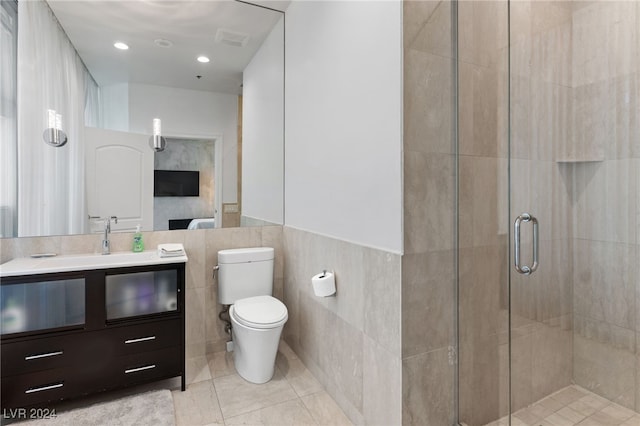 bathroom featuring toilet, visible vents, vanity, tile walls, and a stall shower