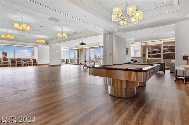 rec room with pool table, a tray ceiling, dark wood-style flooring, and an inviting chandelier