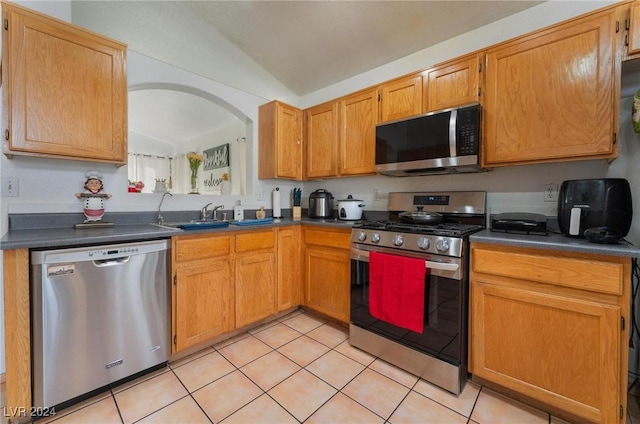 kitchen with stainless steel appliances, lofted ceiling, sink, and light tile patterned floors