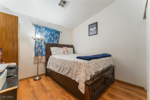 bedroom with vaulted ceiling and hardwood / wood-style floors