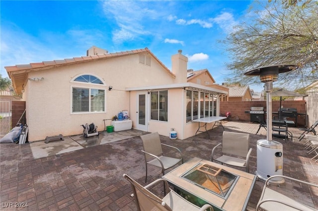 back of property featuring a patio area, a sunroom, and an outdoor fire pit