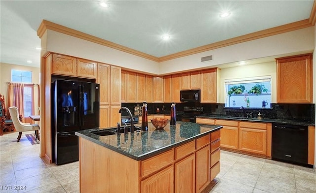 kitchen with a kitchen island with sink, sink, black appliances, and dark stone countertops