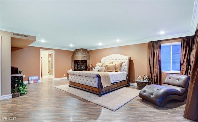 bedroom with ornamental molding, wood-type flooring, and connected bathroom