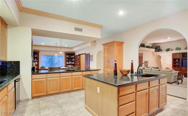 kitchen with decorative light fixtures, dishwasher, an island with sink, sink, and dark stone counters