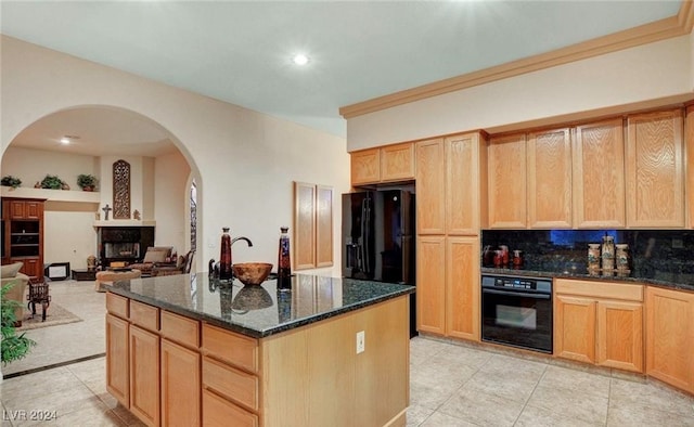 kitchen featuring dark stone countertops, backsplash, a center island, black appliances, and light tile patterned flooring