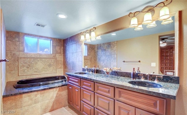 bathroom featuring ceiling fan, tile walls, a relaxing tiled tub, vanity, and tile patterned floors