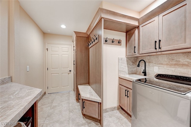 interior space with light brown cabinetry, sink, washer / dryer, and backsplash