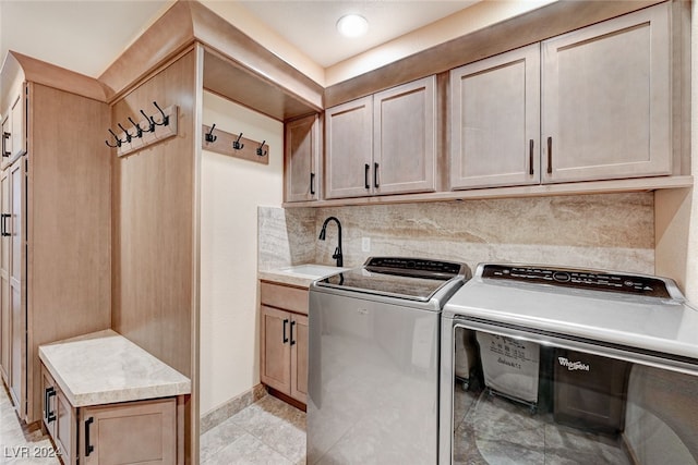 clothes washing area with cabinets, sink, and washer and clothes dryer