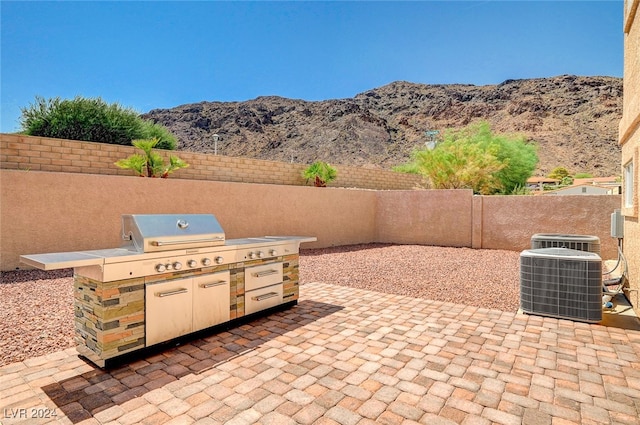 view of patio / terrace featuring cooling unit, a mountain view, a grill, and an outdoor kitchen