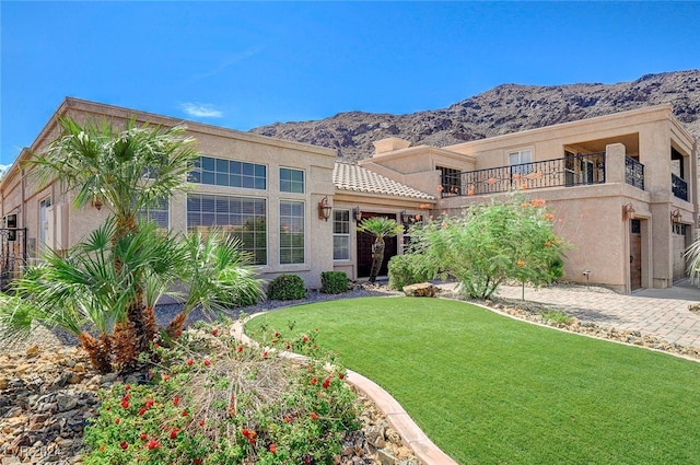 view of front of house with a mountain view, a front lawn, and a balcony