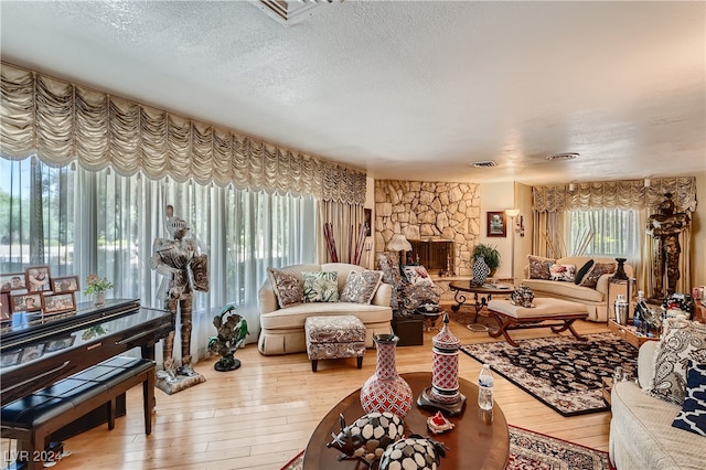 living room with a fireplace, a textured ceiling, and light hardwood / wood-style floors