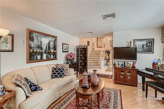 living room featuring light hardwood / wood-style flooring, a textured ceiling, and an inviting chandelier