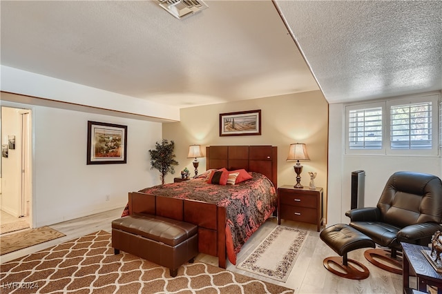 bedroom featuring a textured ceiling and light hardwood / wood-style floors