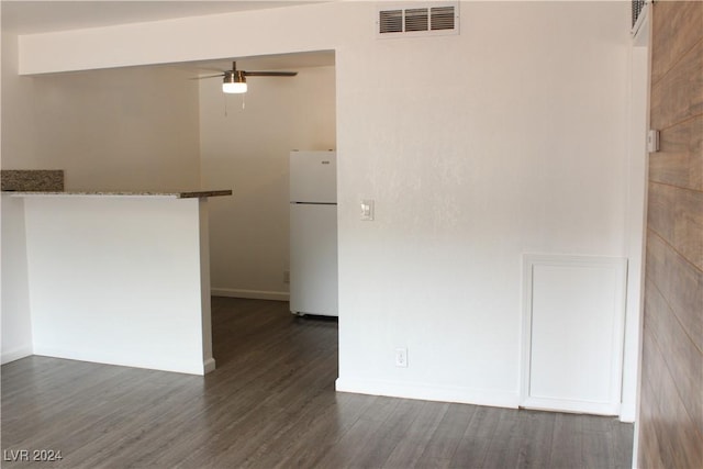 interior space with a ceiling fan, visible vents, dark wood-style flooring, and baseboards