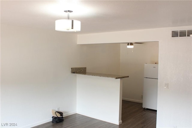 kitchen with visible vents, stone countertops, dark wood finished floors, freestanding refrigerator, and baseboards