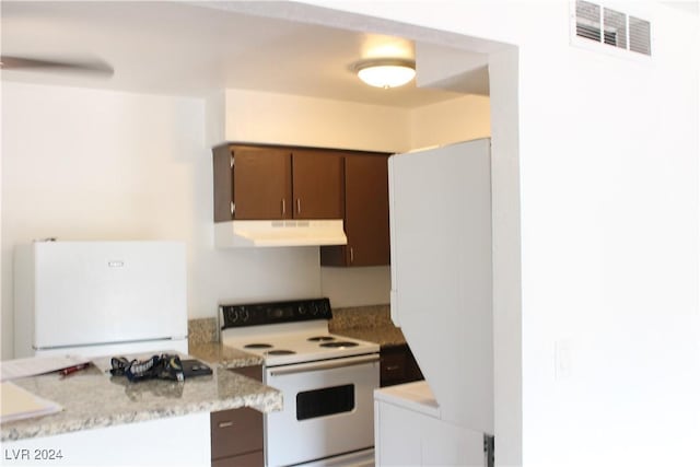 kitchen featuring under cabinet range hood, visible vents, white appliances, and light countertops