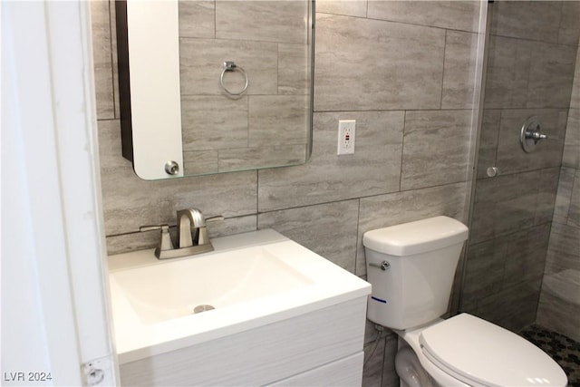 bathroom with toilet, tile walls, vanity, and a tile shower