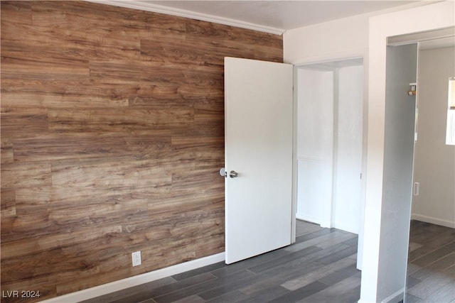 unfurnished bedroom with baseboards, wooden walls, and wood finished floors