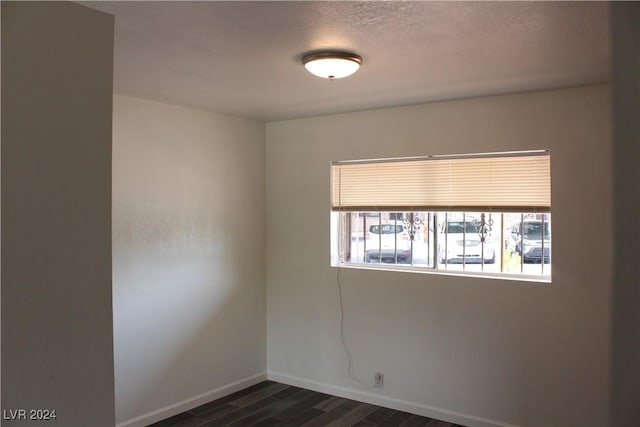 unfurnished room featuring dark wood-style floors, a textured ceiling, and baseboards