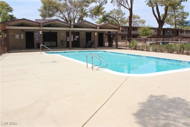 community pool with a patio and fence