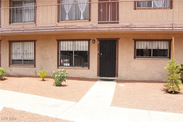 entrance to property with a balcony and stucco siding