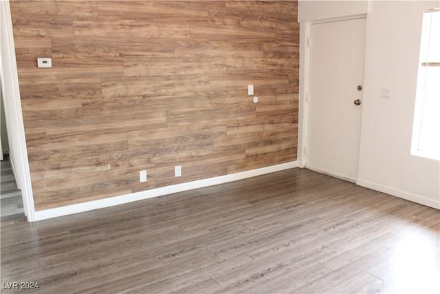 spare room featuring baseboards, wooden walls, and wood finished floors