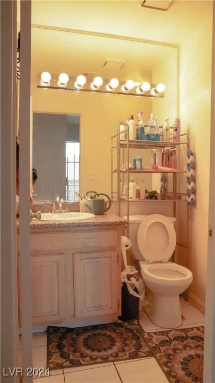 half bathroom with toilet, vanity, and tile patterned floors