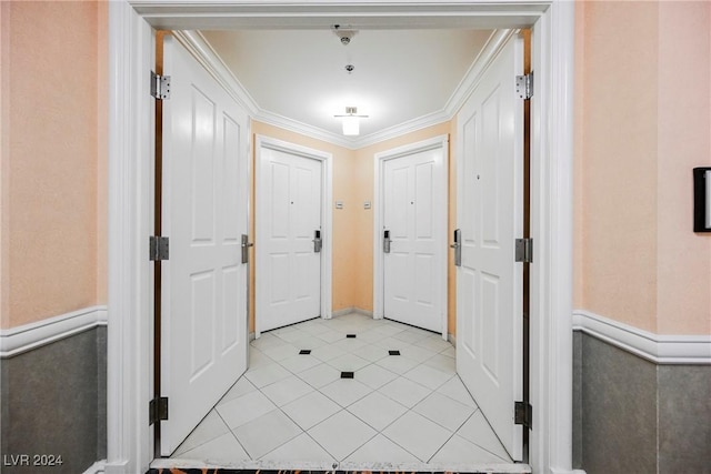 foyer entrance featuring crown molding, light tile patterned floors, and wainscoting