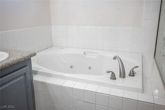 bathroom featuring vanity and tiled bath